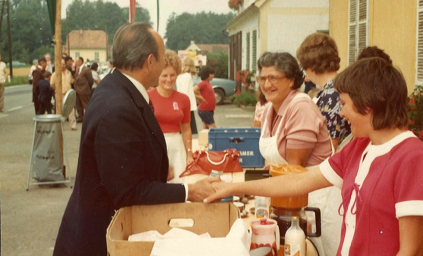 Frau Maria Leitzinger (Dame mit Brille) schupft den Kaffeestand vor dem Gemeindewohnhaus im Rahmen der Schlauchbootweihe der FF Altneudörfl und schenkt LH Stellvertreter Franz Wegart ein Lächeln, 1974. Foto: FF Altneudörfl